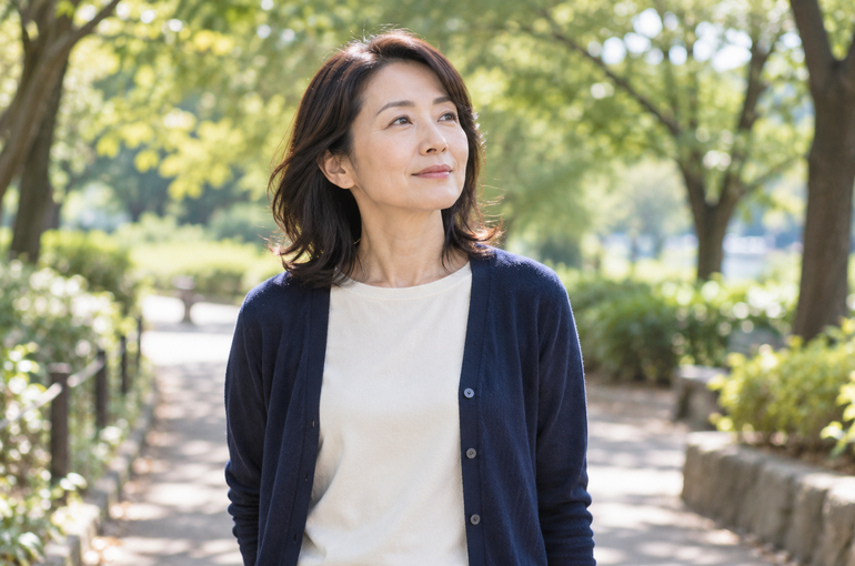木々のある道で立ち止まり、考えを巡らせる女性